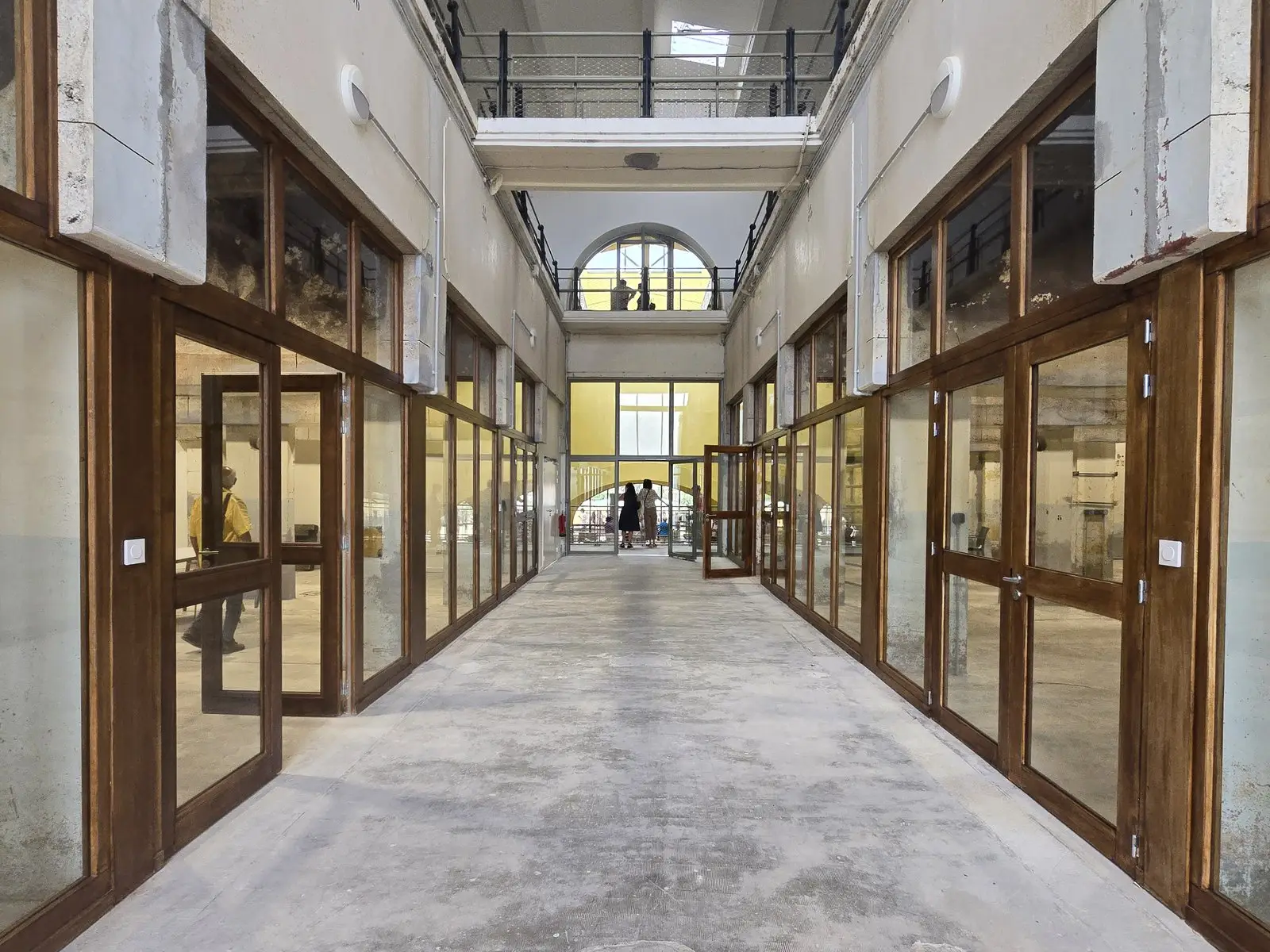 La même allée après transformation : ateliers vitrés à menuiseries bois de part et d'autre
