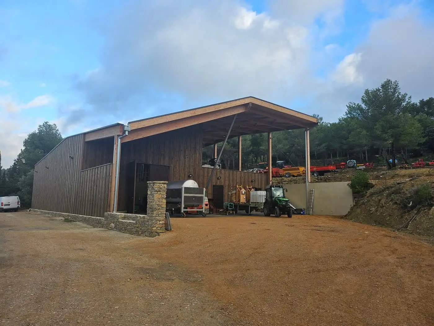 La cave terminée : bardage bois, soubassement en pierre et auvent de réception de vendange