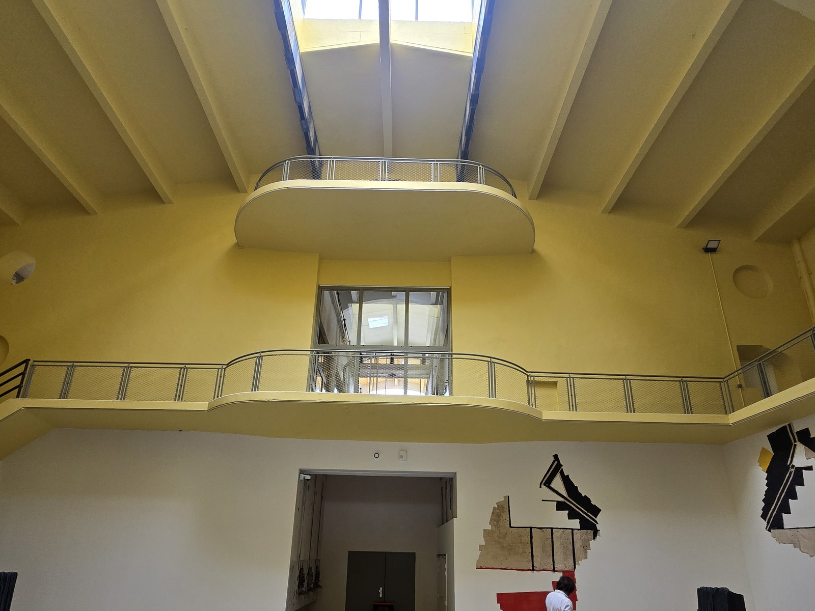 Le même hall après transformation en lieu d'art, murs jaunes et passerelle neuve