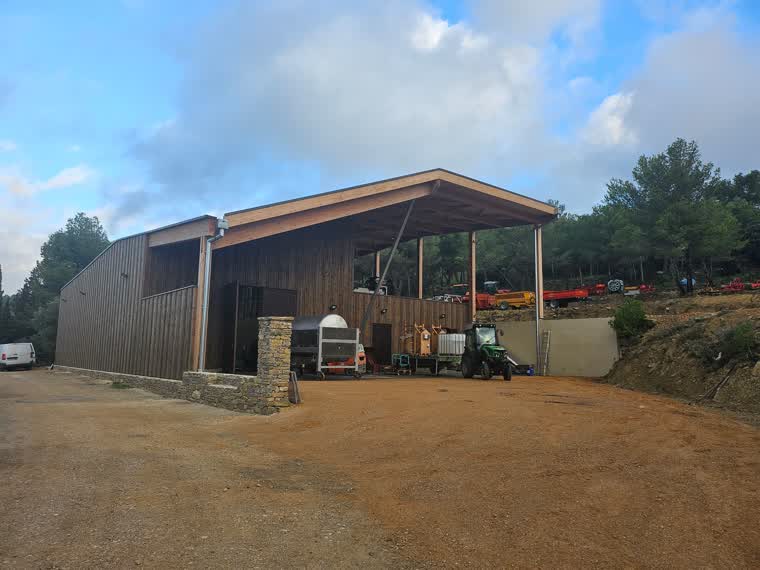 Cave particulière en bardage bois avec soubassement en pierre et auvent de réception de vendange