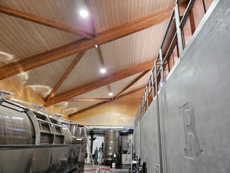Chai de vinification sous charpente en lamellé-collé, avec cuves inox et cuverie béton