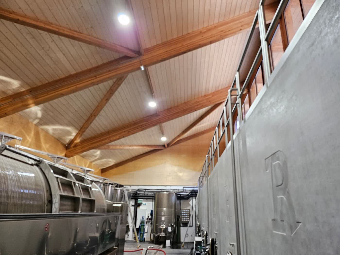 Chai de vinification sous charpente en lamellé-collé, avec cuves inox et cuverie béton