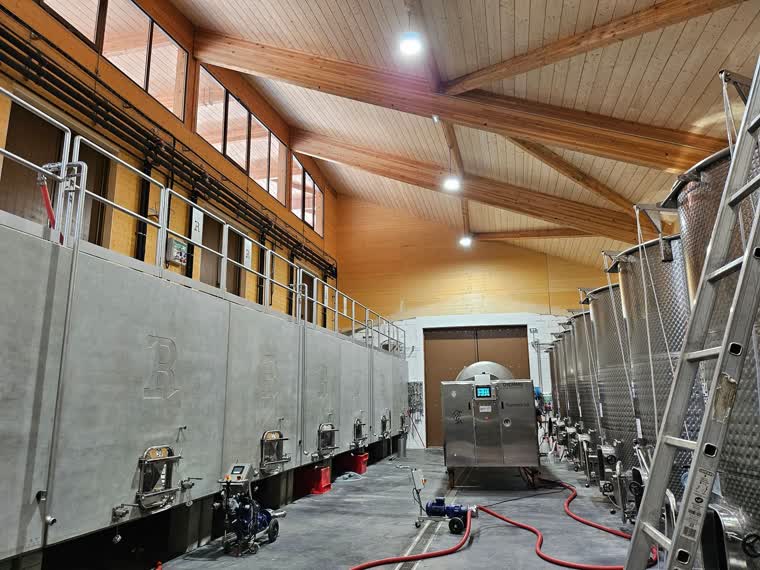Cuverie d'une cave de vinification : cuves béton, cuves inox et charpente bois apparente