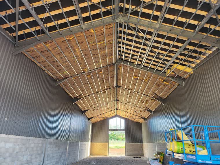 Intérieur d'un hangar agricole : charpente métallique, isolation de toiture et bardage