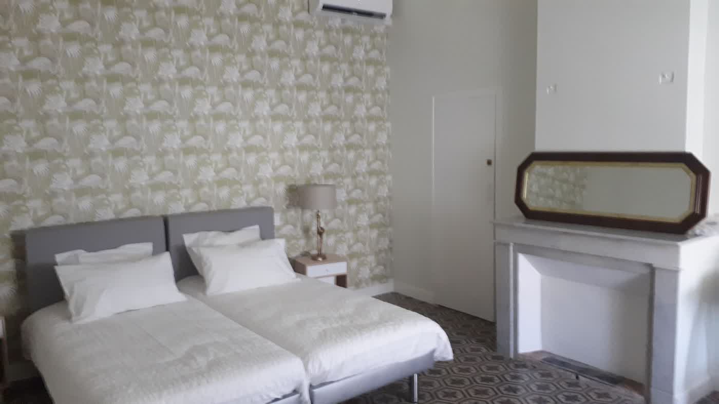 Chambre contemporaine après rénovation, murs clairs et literie blanche