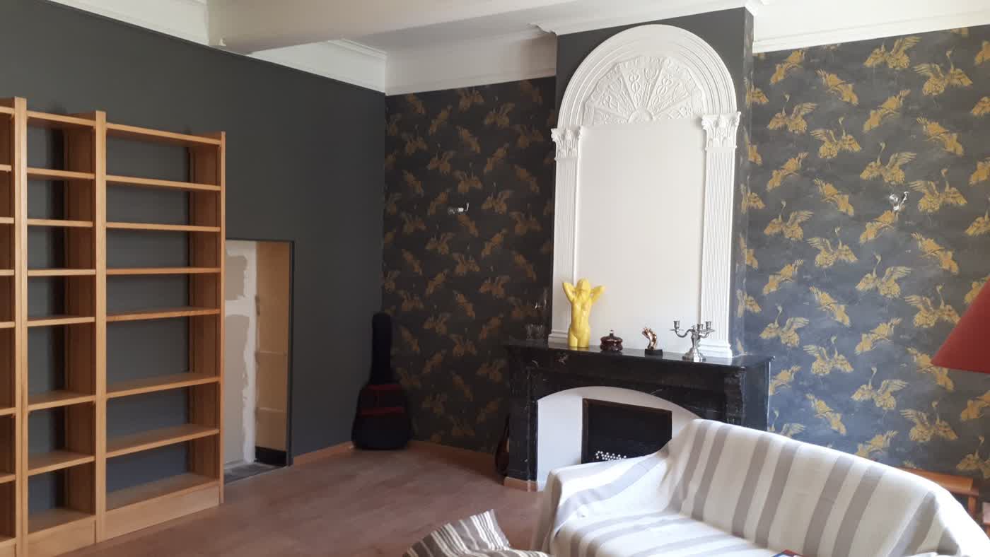 Salle à manger de gîte après rénovation, murs sombres à motifs et cheminée restaurée