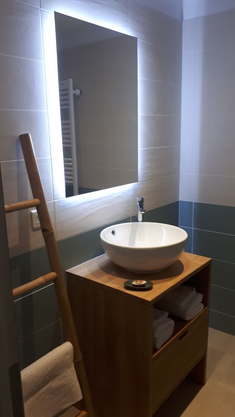Salle d'eau de gîte avec vasque, miroir rétroéclairé et échelle porte-serviettes en bambou