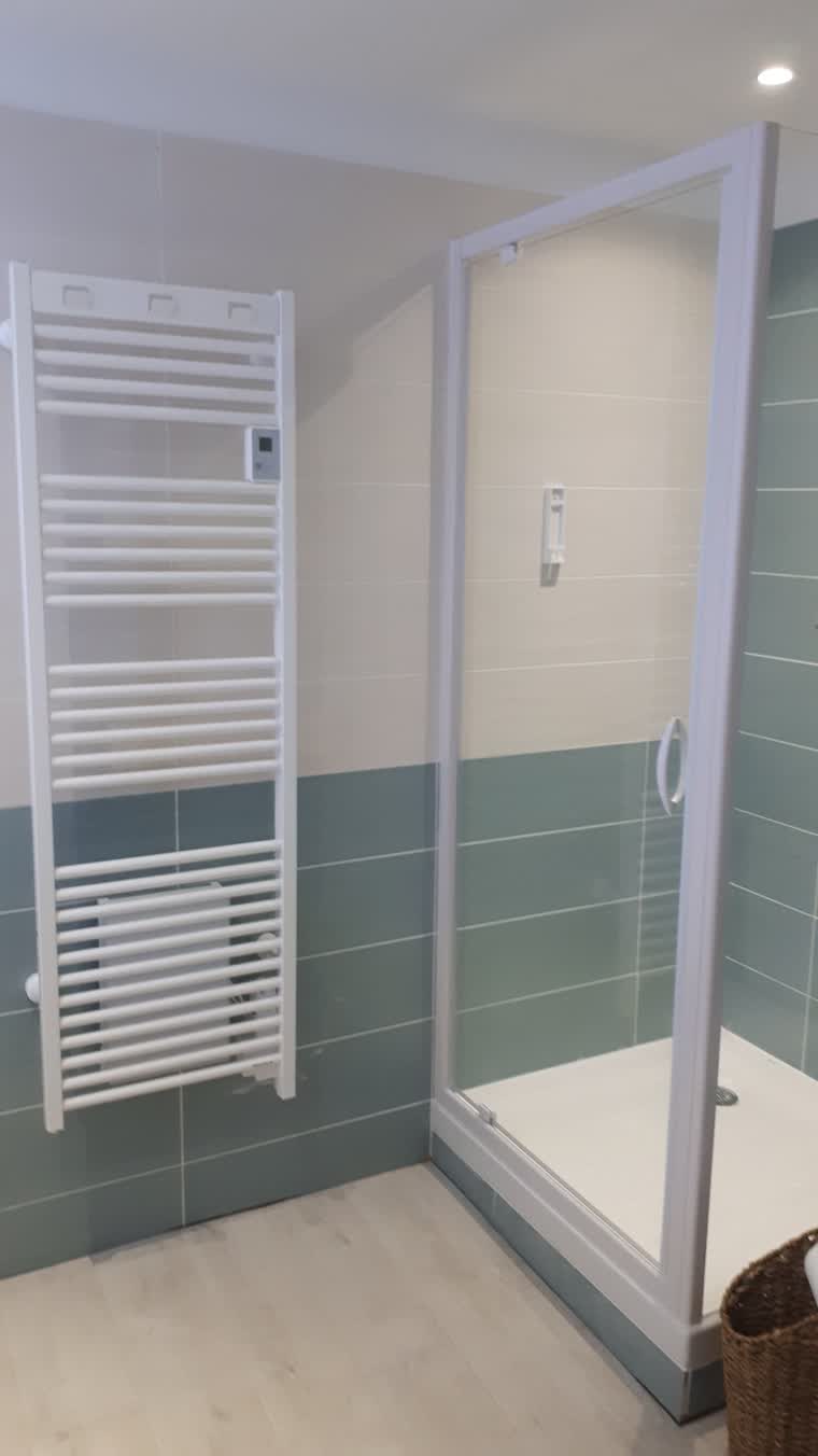 Salle d'eau avec cabine de douche et sèche-serviettes après rénovation